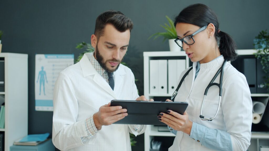 Two clinicians reviewing a digital health app on a tablet